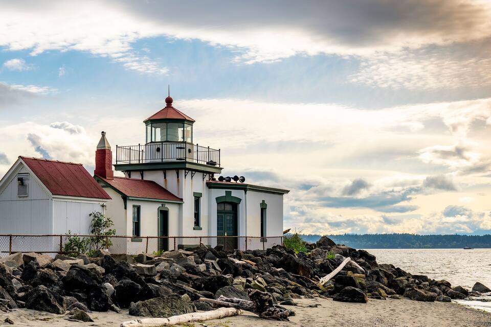 A lighthouse on a rocky shore with a clear sky.