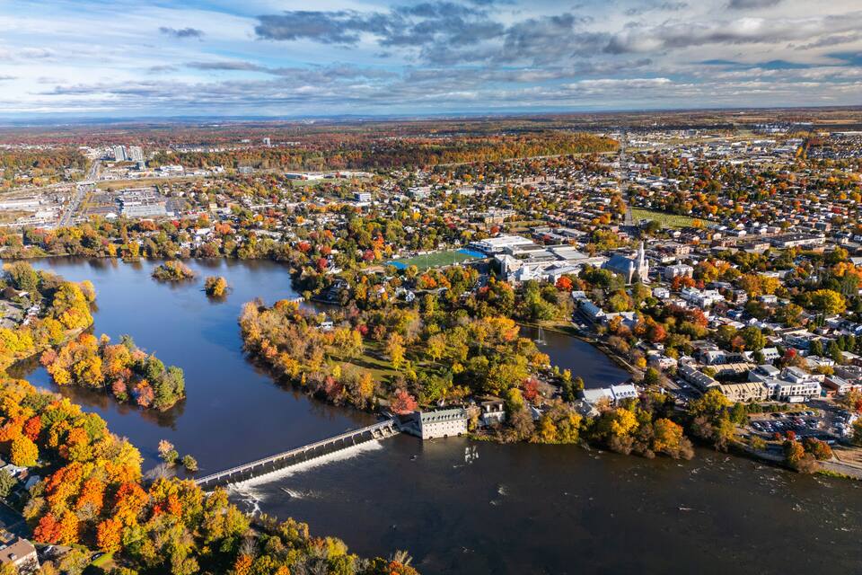 A river with a dam and surrounding autumn foliage.
