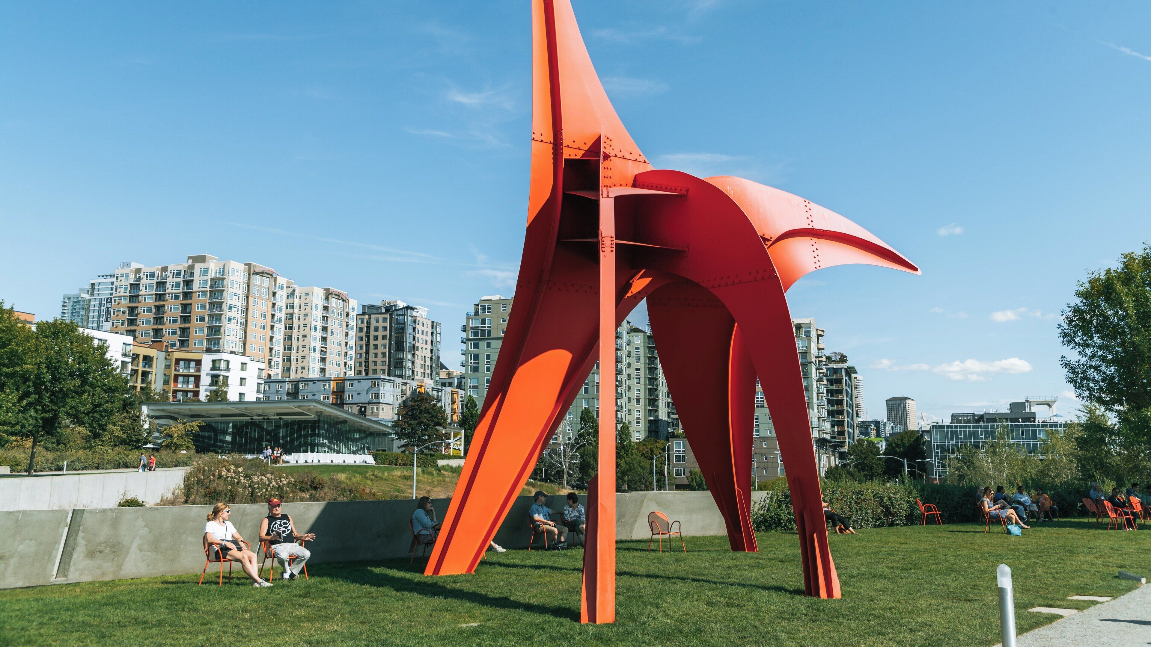 Visitors enjoying the Olympic Sculpture Park featuring modern art installation in downtown Seattle, Washington on a sunny day