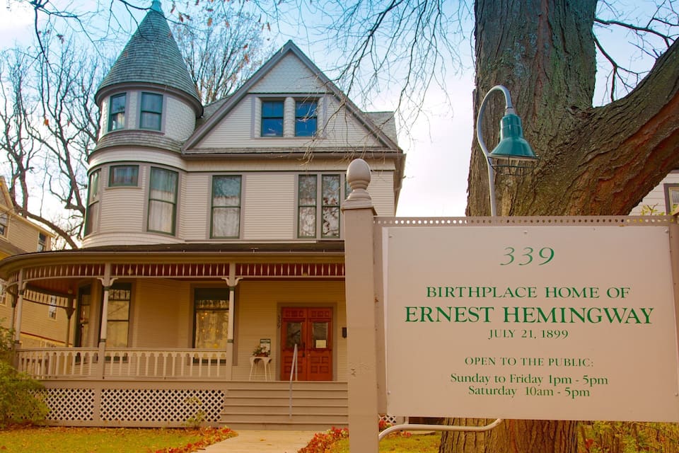 Una casa histórica con porche, una torre y un cartel que indica que es el lugar de nacimiento de Ernest Hemingway.