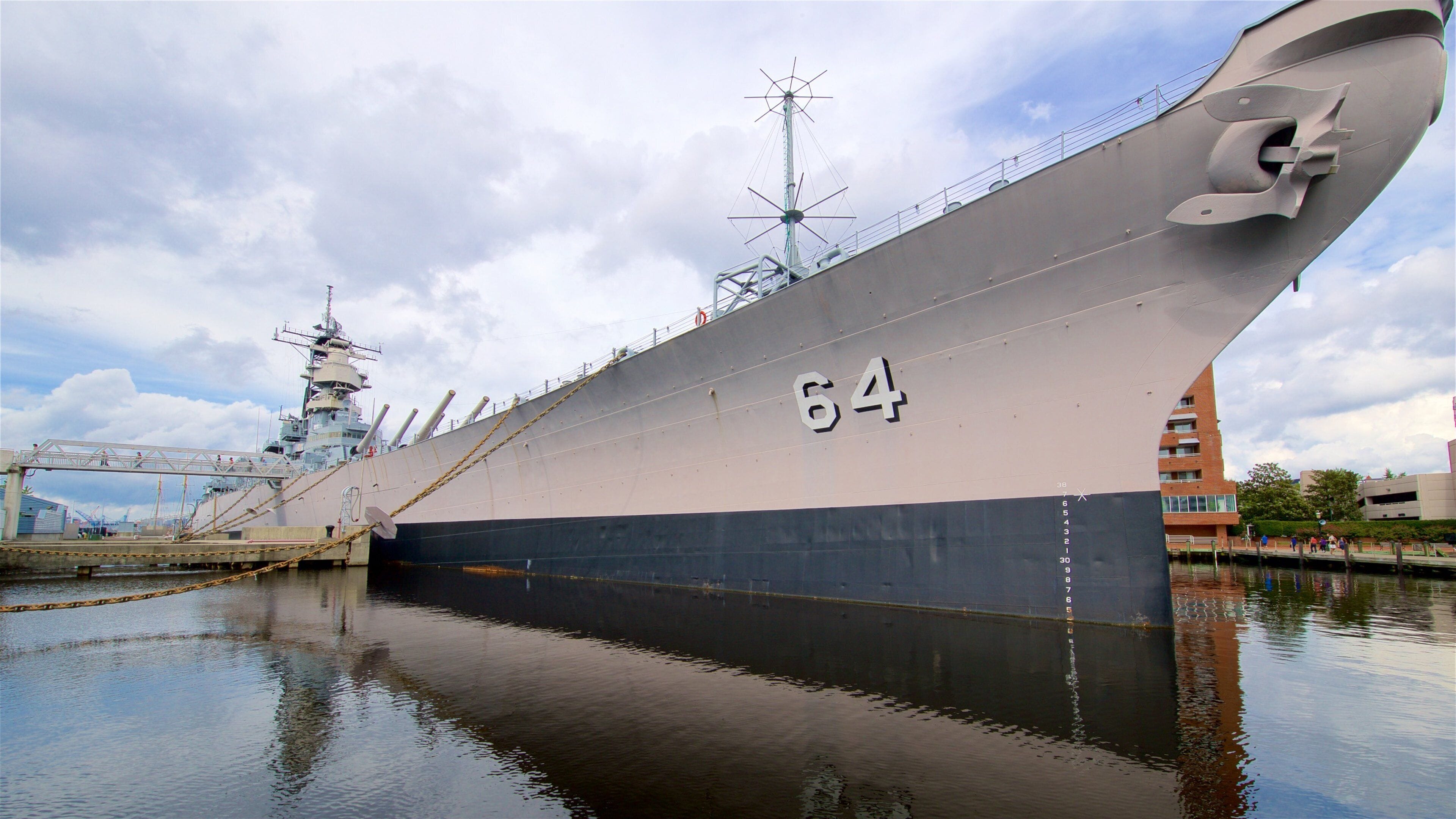 A large ship with the number 64 on its side docked at a port.