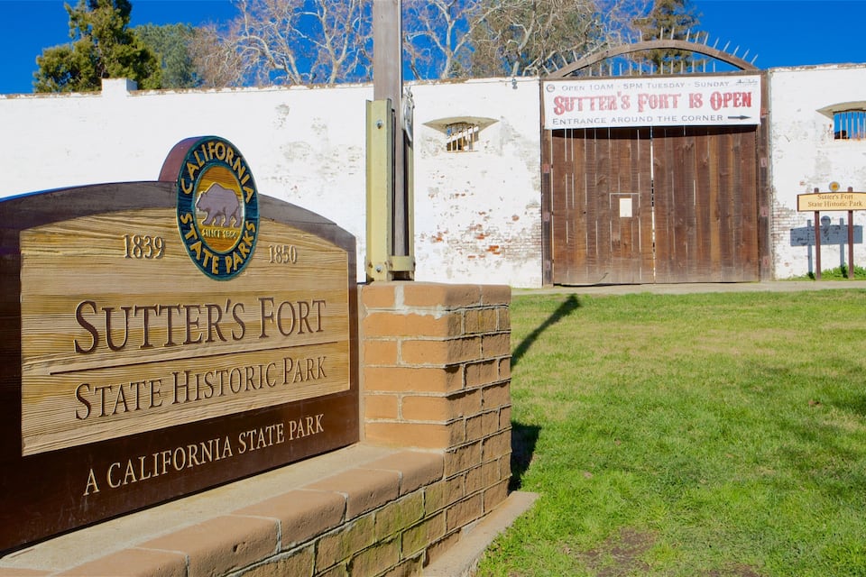 A wooden sign for Sutter's Fort State Historic Park with a California state seal and dates 1839-1850.