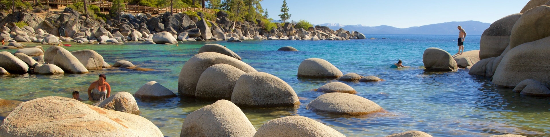 A clear lake surrounded by large boulders and trees.