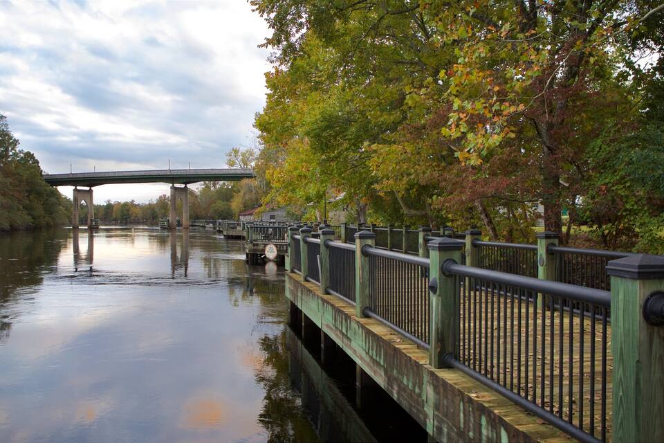 A bridge over a calm river with autumn foliage.