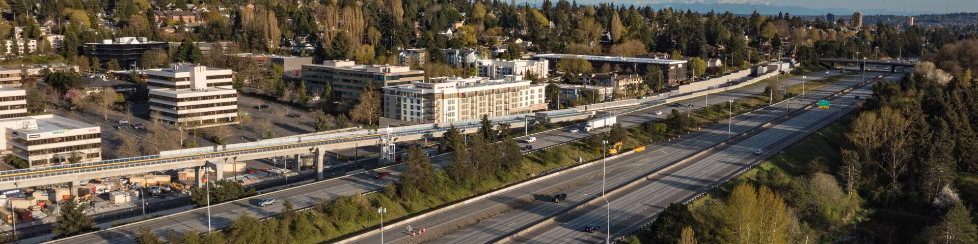 Aerial view of I-5 highway surrounded by buildings and trees under a blue sky, Northgate, Seattle, United States.