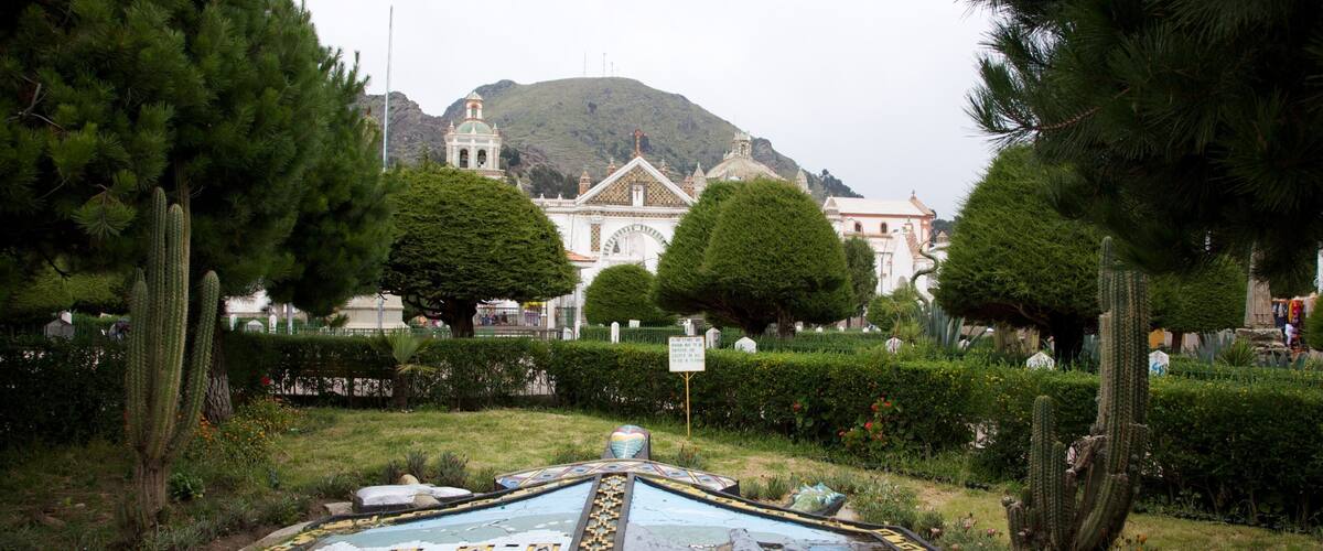 A large, circular mosaic with a central figure, surrounded by cacti and trees, with a building in the background.