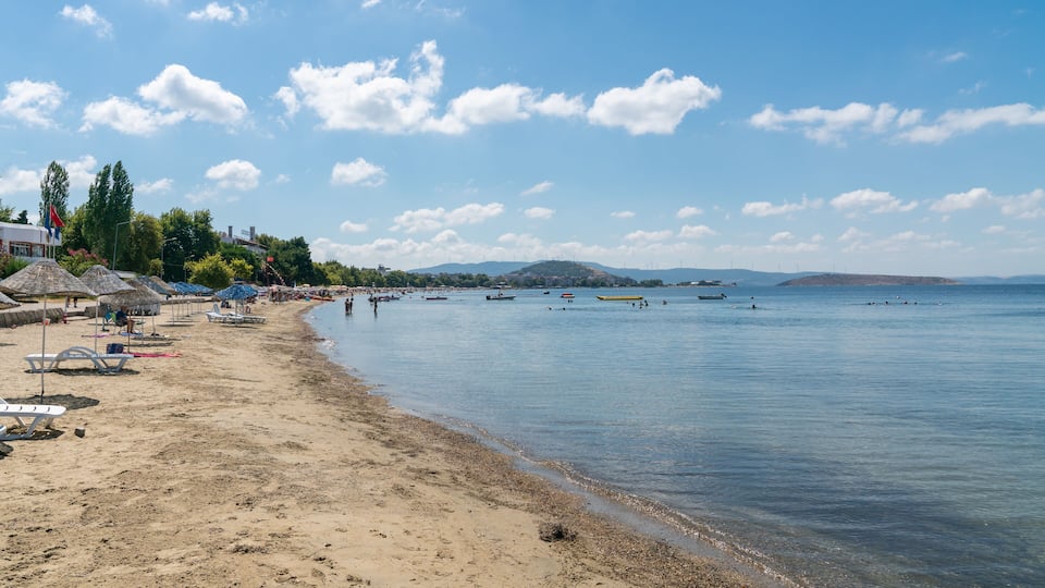 A beach with umbrellas, boats, and a clear sky.