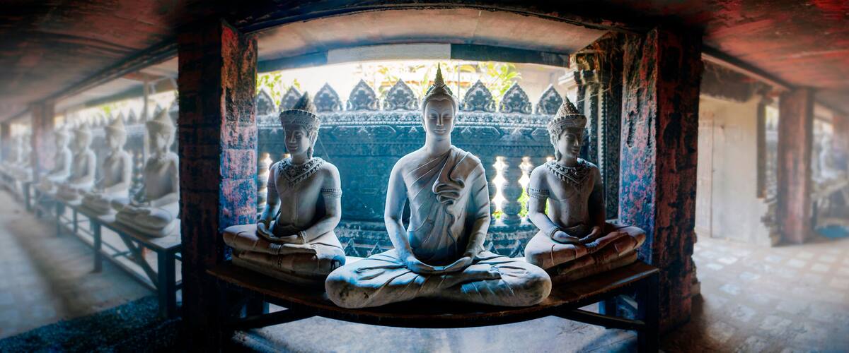A row of seated Buddha statues in a temple corridor.