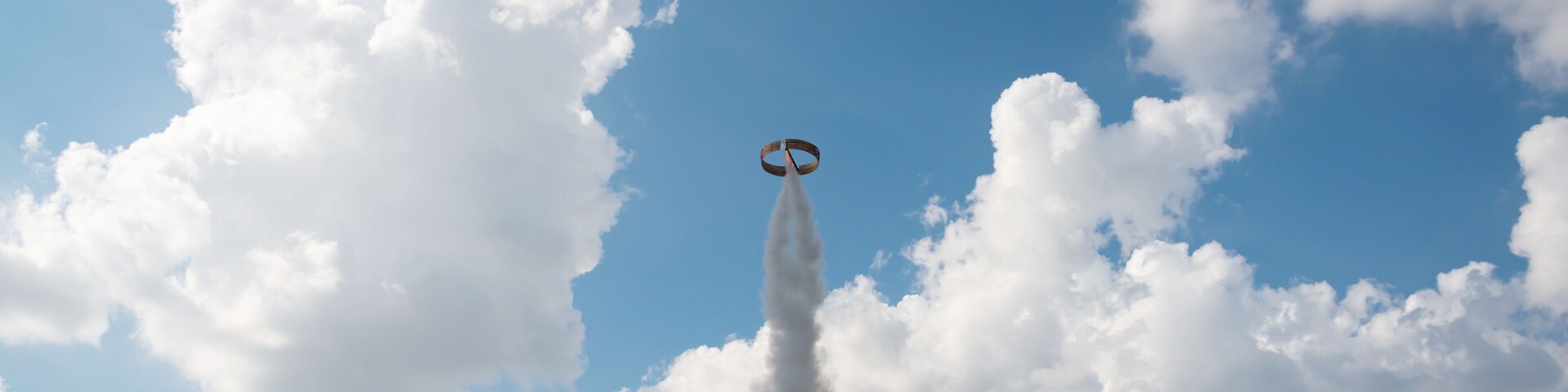 Un globo aerostático con una estela de humo sobre un fondo de nubes.