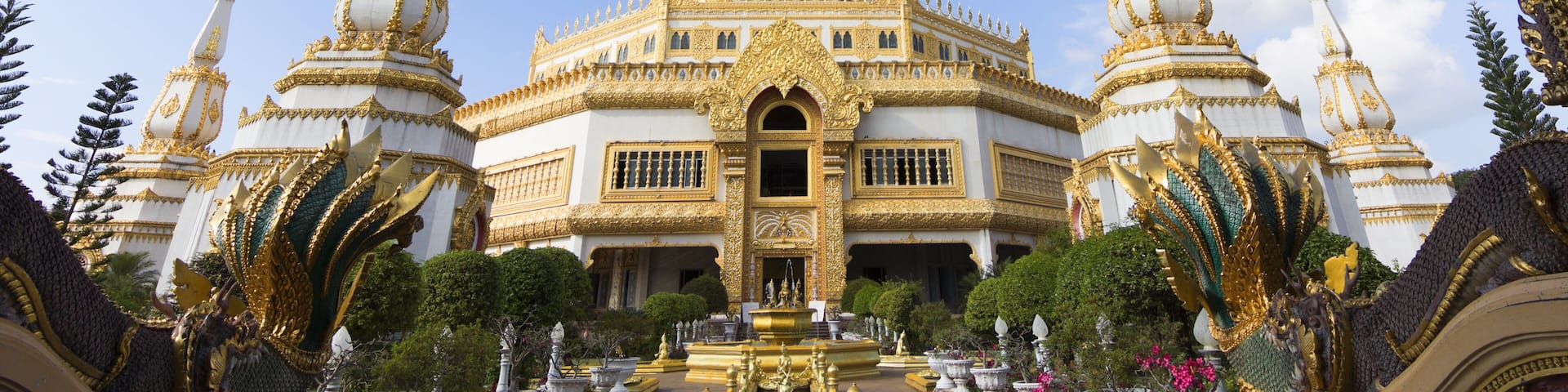 A large white and gold temple with multiple spires and a central statue.