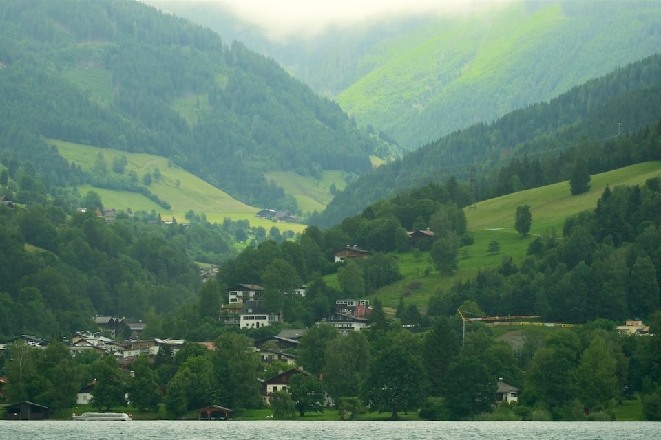 Un lac entouré de collines verdoyantes et de maisons.