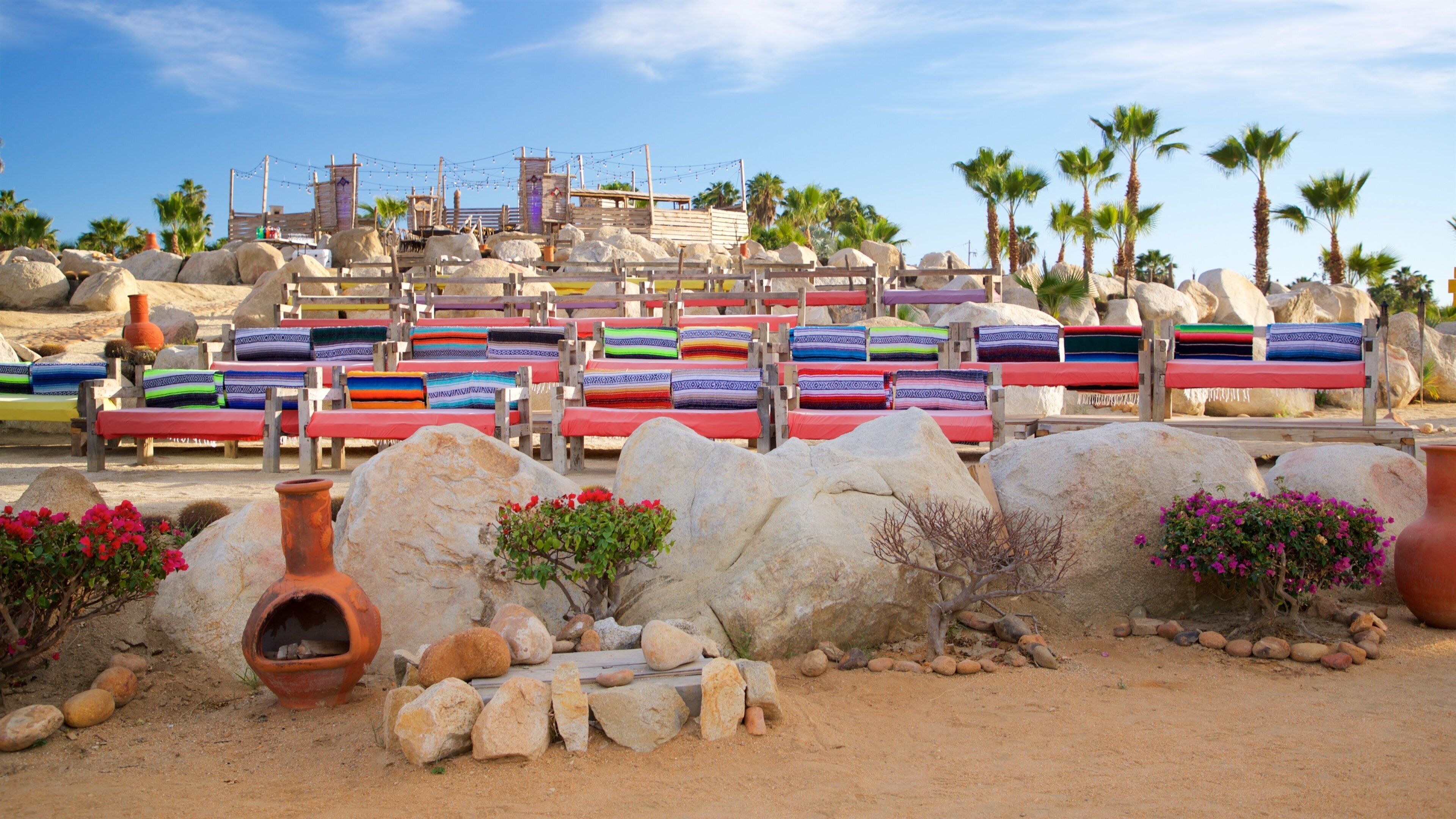 Une plage avec des chaises longues colorées et de gros rochers.
