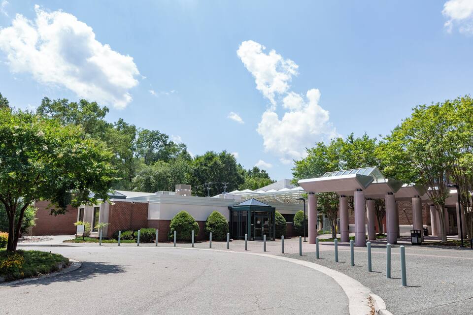 A building with a covered entrance, surrounded by trees and a clear sky.