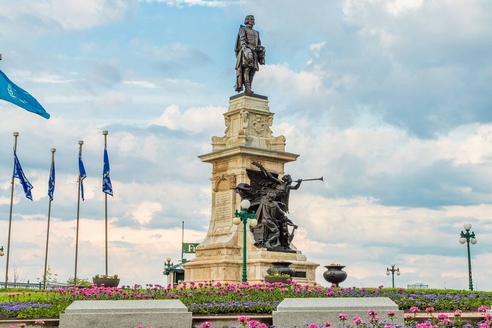 A statue of a man in a suit, surrounded by flowers and flags.