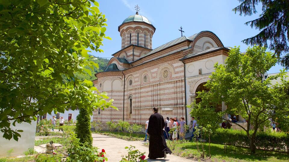 A historic church with a prominent dome and bell tower, surrounded by lush greenery and a well-maintained garden.