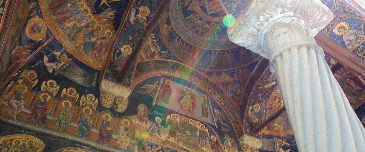 A ceiling with intricate religious artwork and a central column.