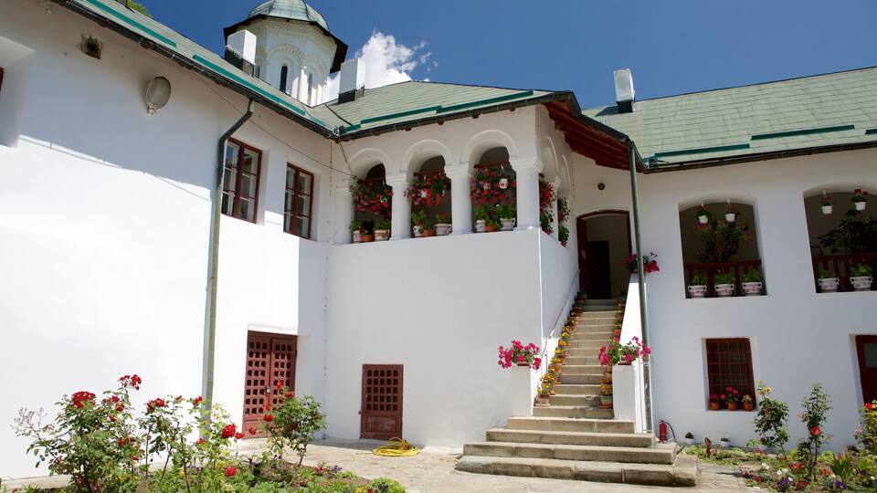 A white building with a green roof, a staircase, and potted flowers.