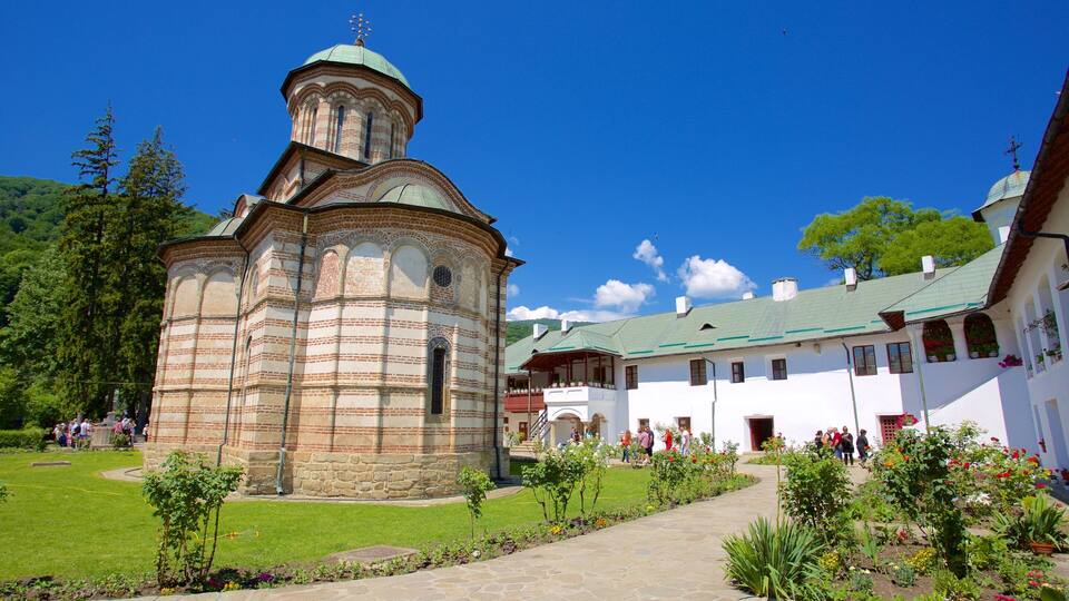 A historic church with a bell tower and a garden with visitors.