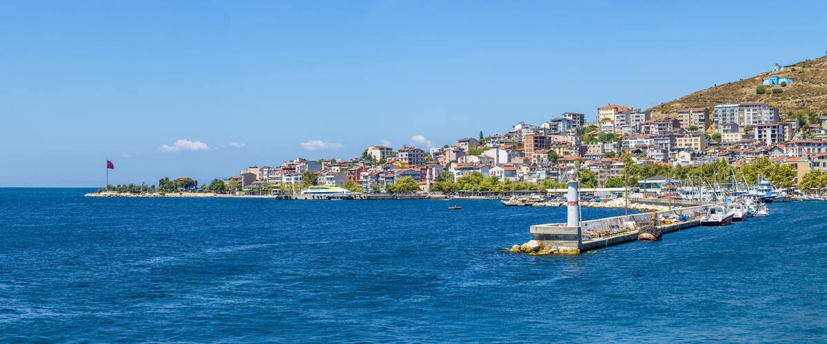A coastal town with buildings along the waterfront, a pier, and boats docked.