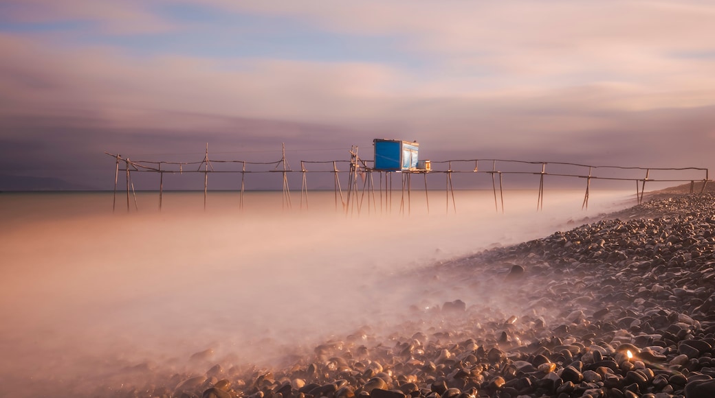 Ein Strand mit einer Holzlattenverkleidung und einer blauen Konstruktion auf Stelzen.