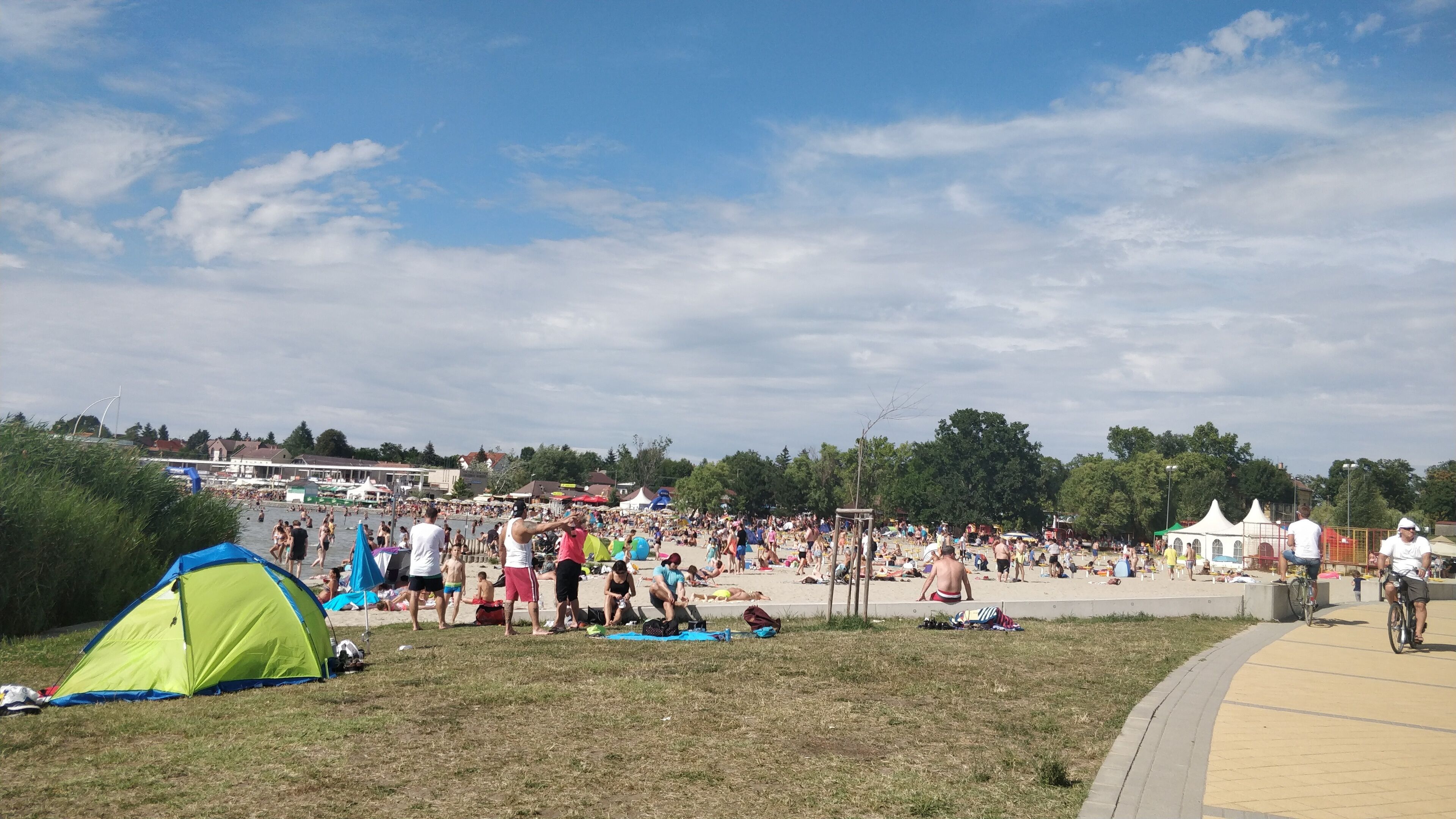 A crowded beach with tents and people relaxing.