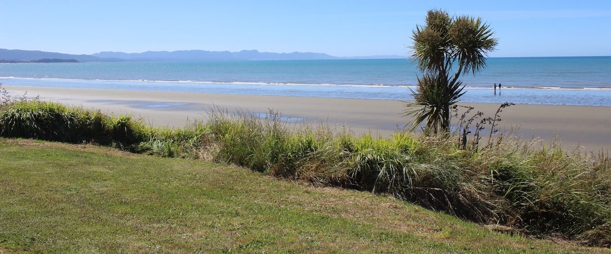 A beach with a clear sky, ocean, and distant mountains.