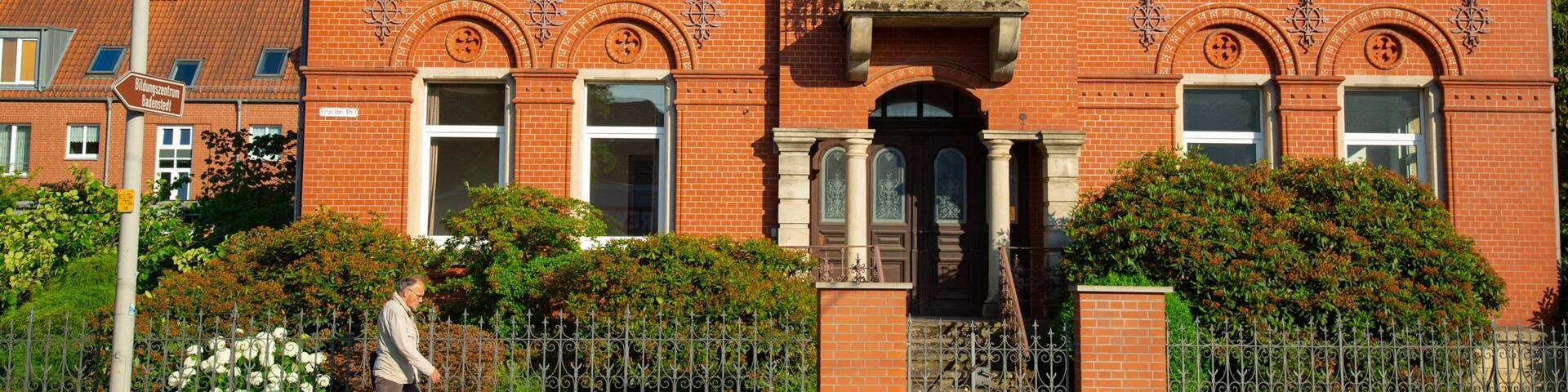 A red brick building with arched windows and a balcony.