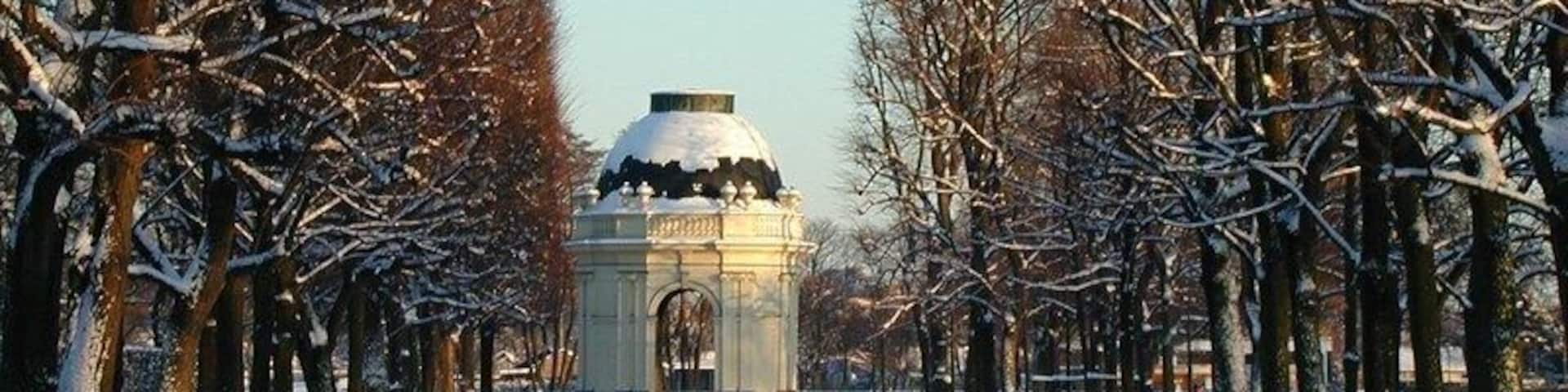 A snow-covered pathway with bare trees and a central structure.