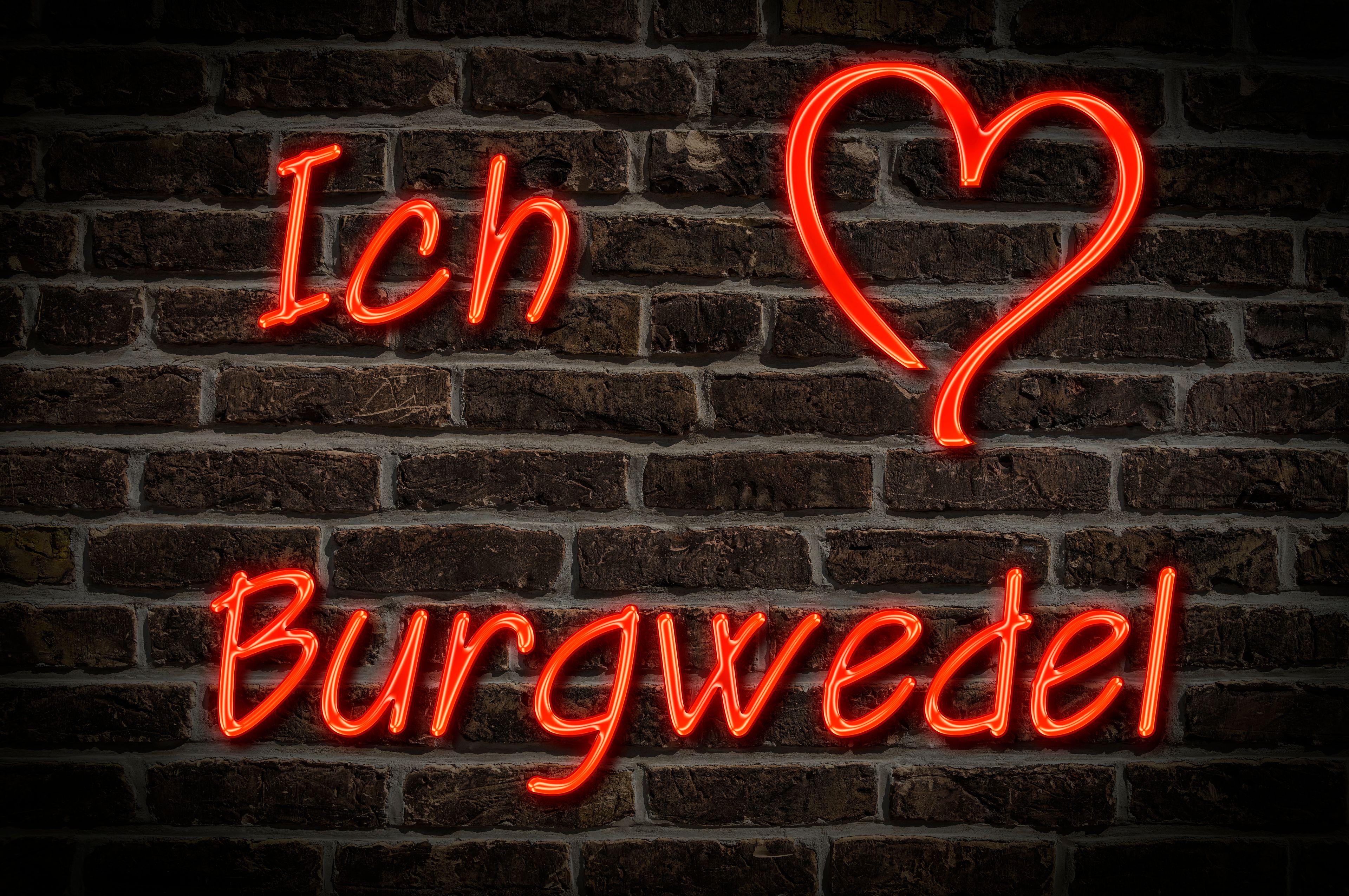 Ein leuchtendes Neonzeichen mit dem Schriftzug 'Ich Burgwedel' an einer Ziegelwand.