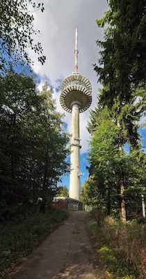 A tall tower with a circular observation deck surrounded by trees.