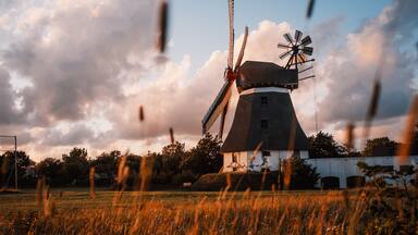 A windmill in a field with a cloudy sky.