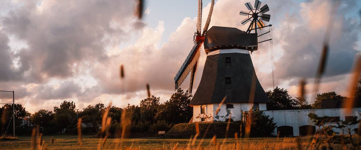 A windmill in a field with a cloudy sky.