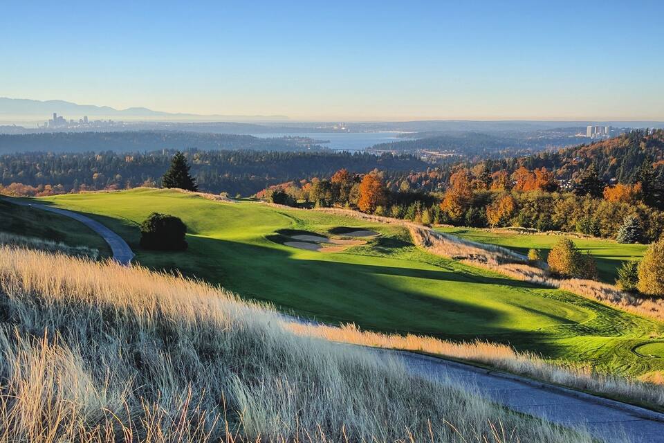 A golf course with a view of a city skyline in the distance.