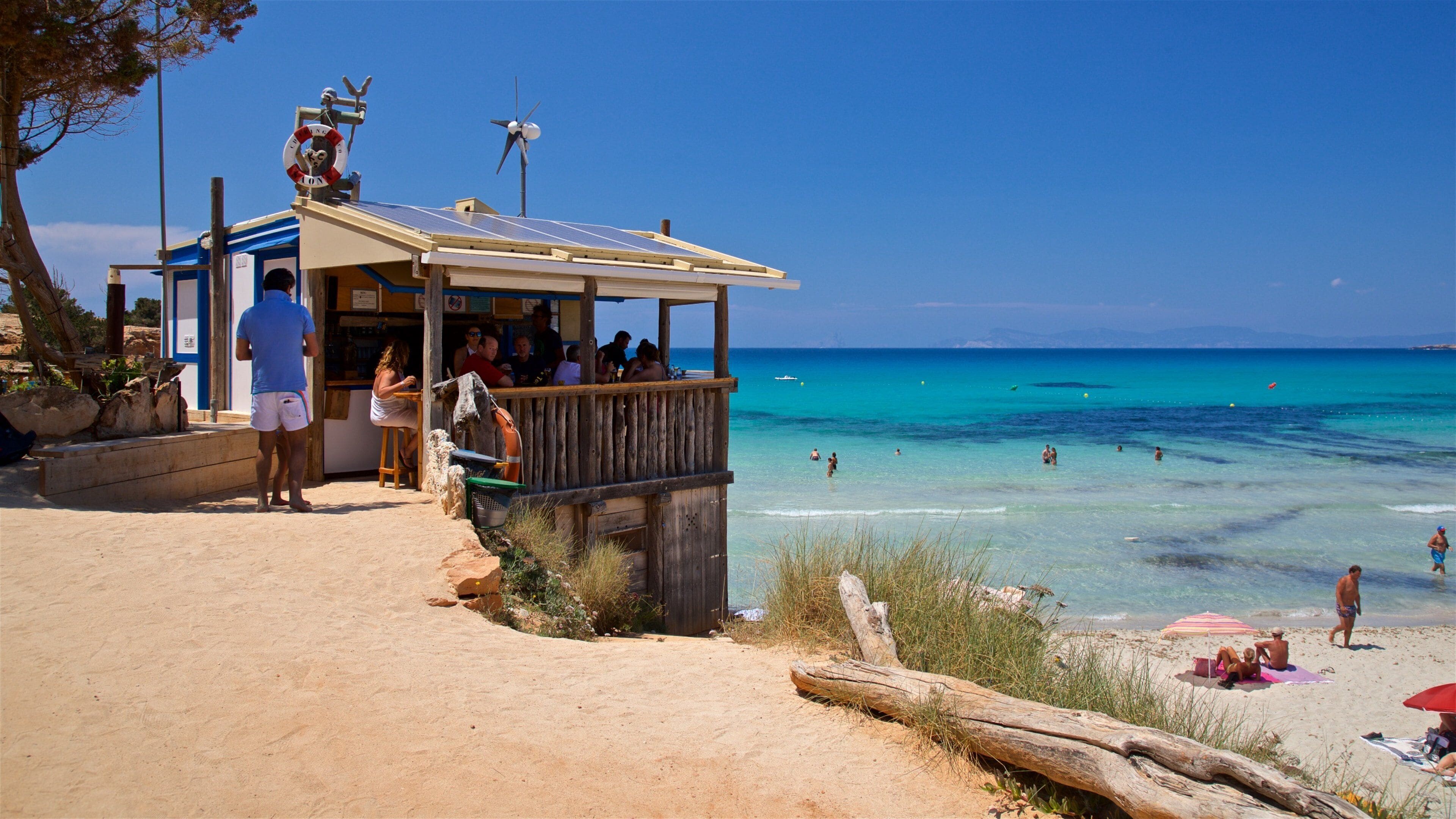 A beachside bar with a wooden deck overlooking turquoise waters.