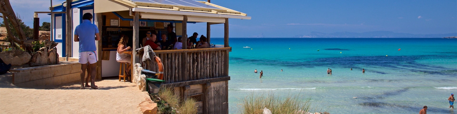 Um bar à beira-mar com um deck de madeira de frente para águas azul-turquesa.