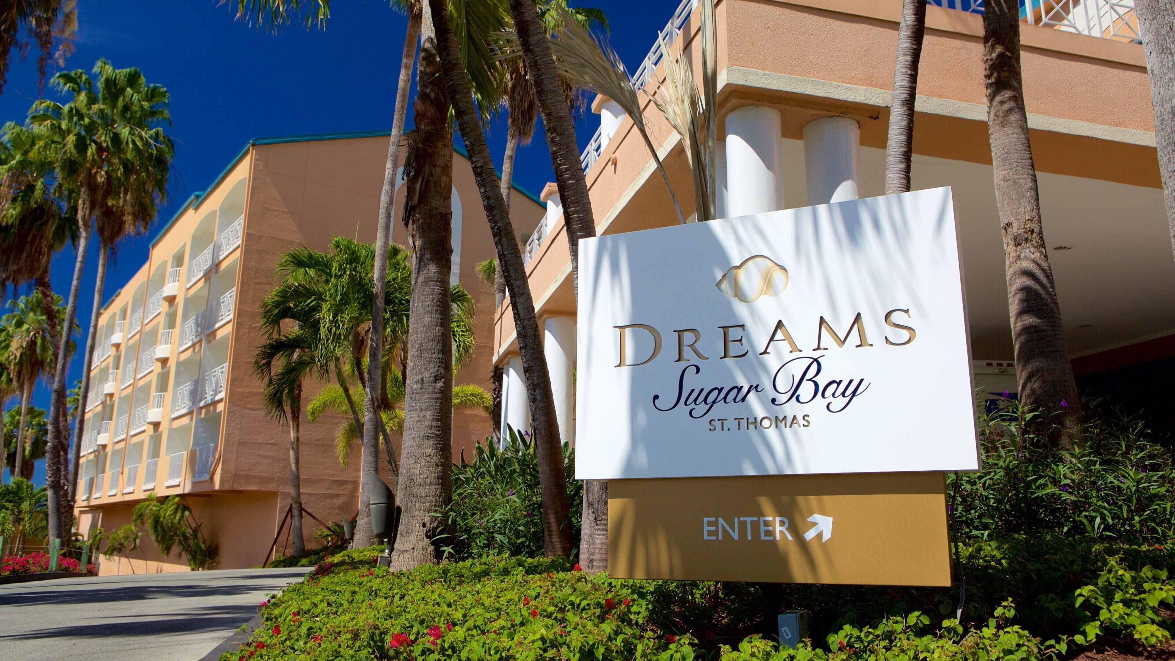 A sign for Dreams Sugar Bay St. Thomas with a palm tree and a building in the background.