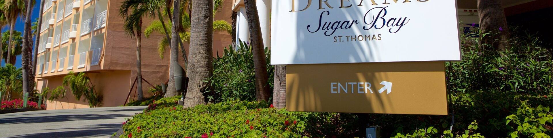 A sign for Dreams Sugar Bay St. Thomas with a palm tree and a building in the background.