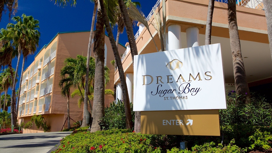 Une enseigne pour l’hôtel Dreams Sugar Bay à Saint-Thomas, avec un palmier et un bâtiment en arrière-plan.