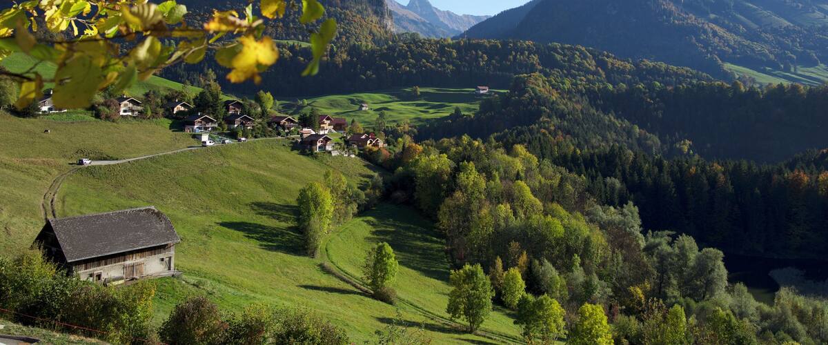 A valley with houses, a winding road, and a mountain range.