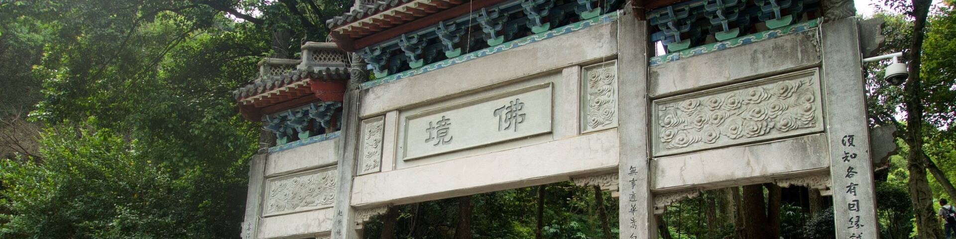 A traditional Chinese gate with inscriptions, surrounded by lush greenery and stone elephants.