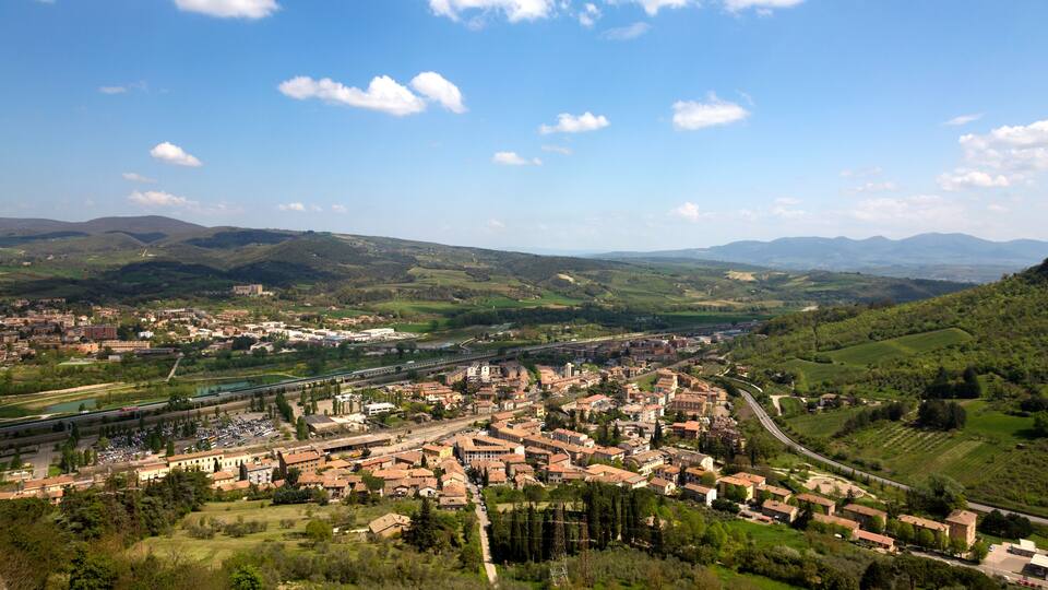A town nestled in a valley with rolling hills in the background.