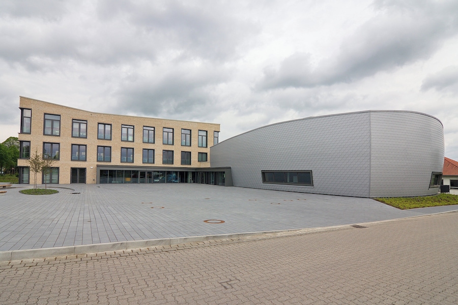 Un bâtiment moderne doté d’une façade incurvée et d’un espace de stationnement à toit plat.