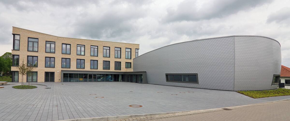 A modern building with a curved facade and a flat-roofed parking area.