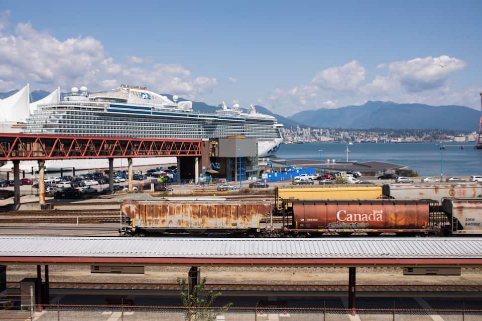 Un crucero atracado en un puerto, con un horizonte urbano y montañas al fondo.