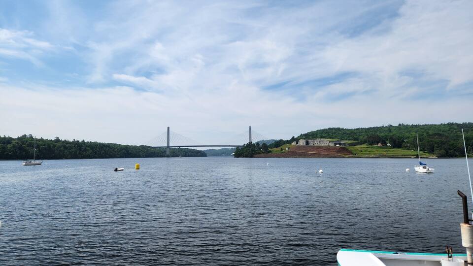 A bridge, calm water, boats, and a forested island.
