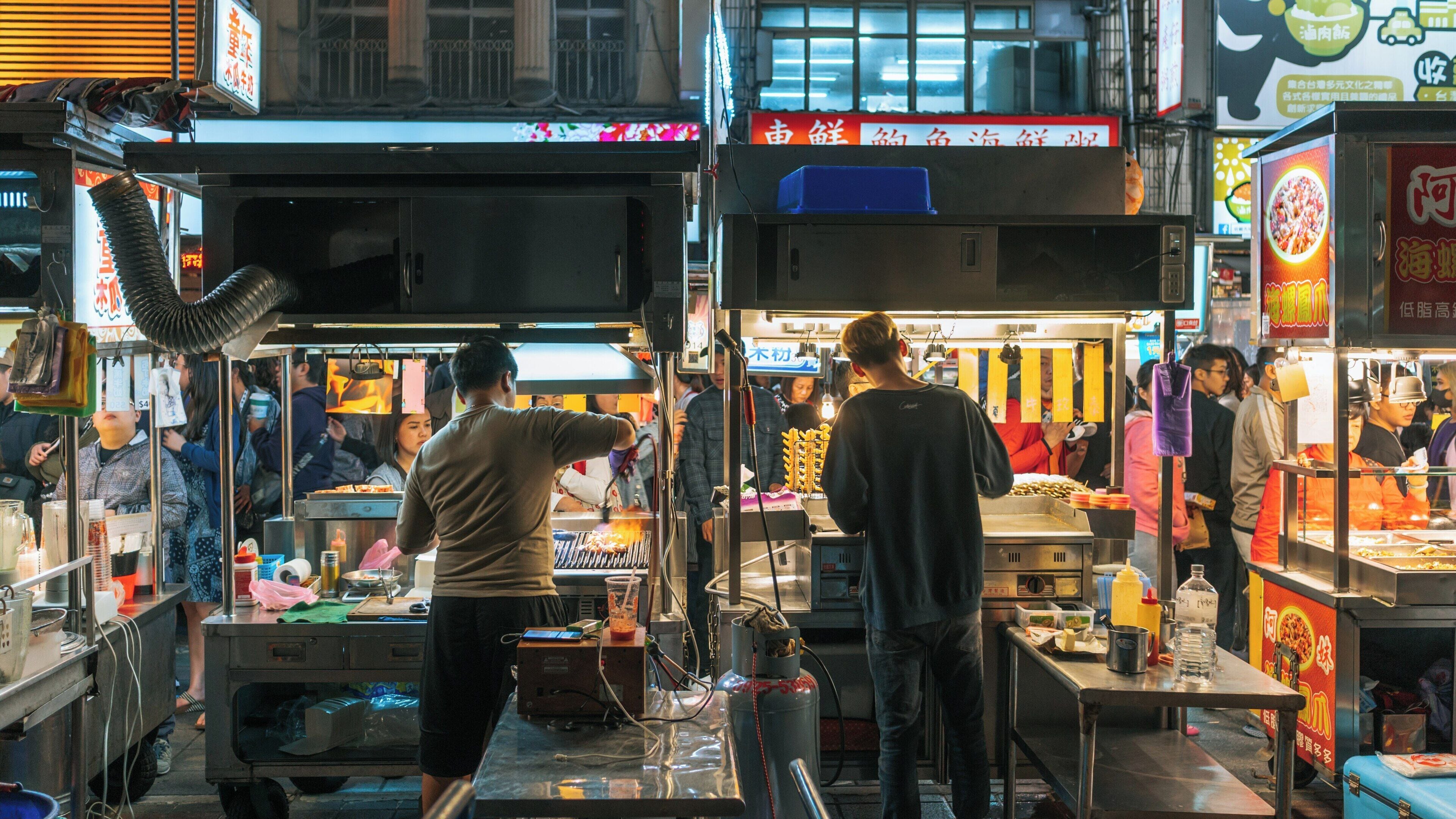 Vibrant energy fills Ningxia Night Market with food vendors serving delicious snacks in Datong, Taipei, Taiwan during an evening stroll