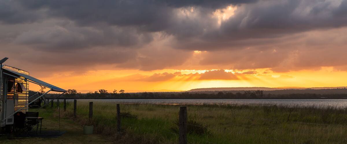 A sunset over a body of water with a cloudy sky.