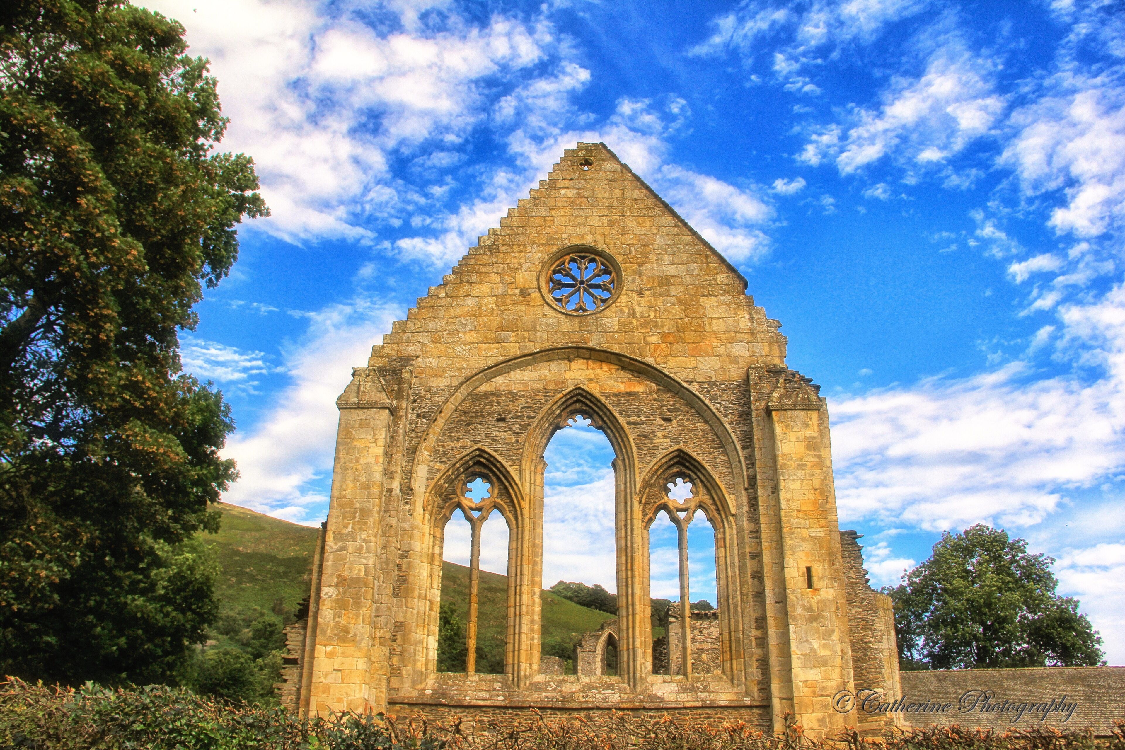 An ancient stone church with a triangular roof and circular window.