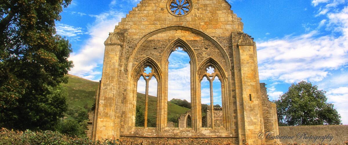 An ancient stone church with a triangular roof and circular window.