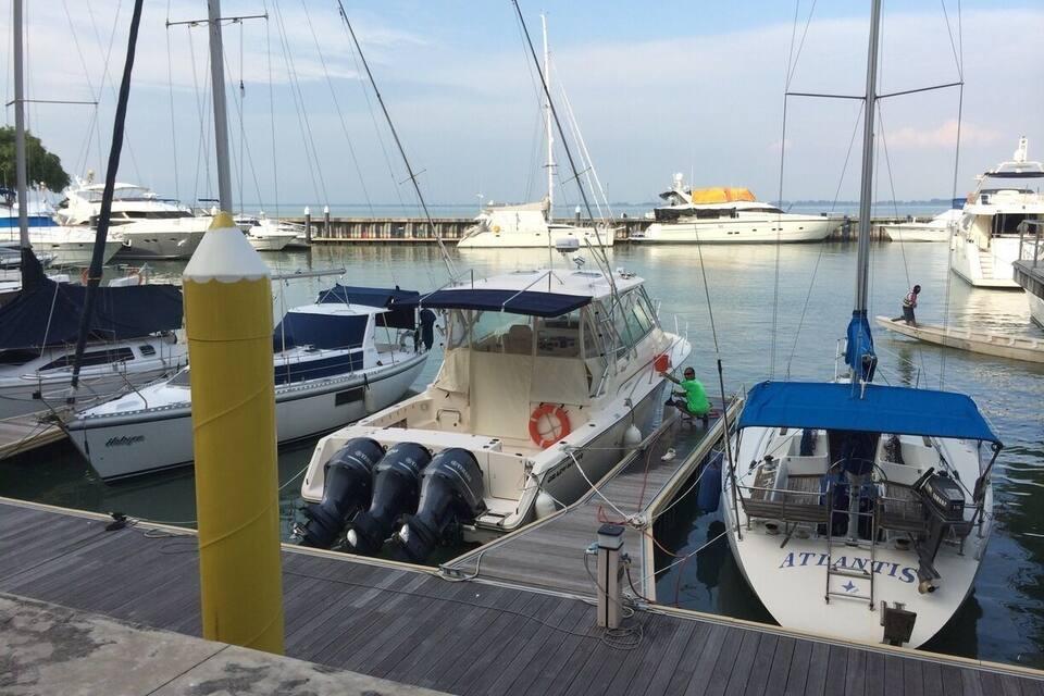 A marina with several boats docked, including a white boat named 'Atlantis' with a blue canopy.